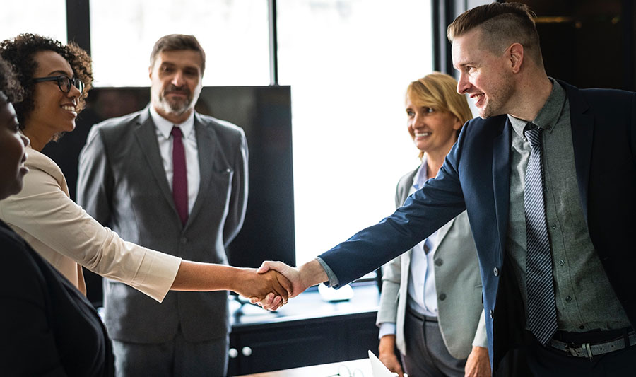 Two business professionals shaking hands in a meeting.