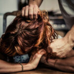 A person tightly grabbing another's hair in an aggressive manner.