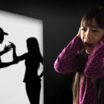 A distressed child watches a shadow of abuse happening.