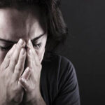 Person covering face with hands, showing distress or sadness.