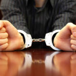 Person in handcuffs resting on a table.