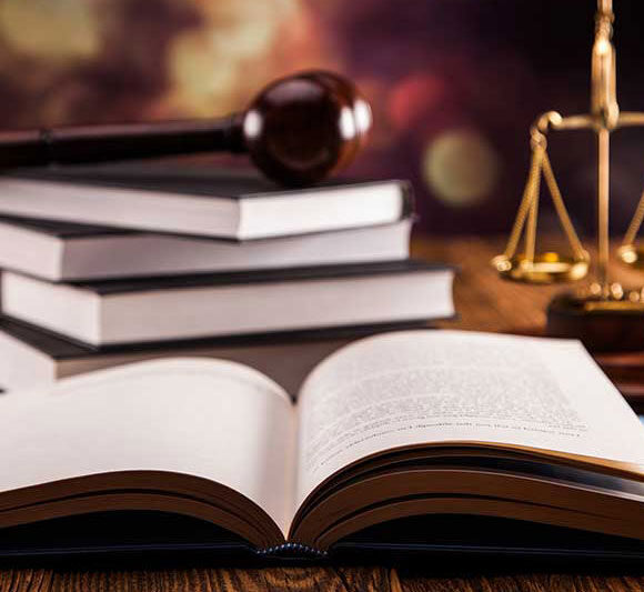 Open law book with gavel and scales of justice in the background.