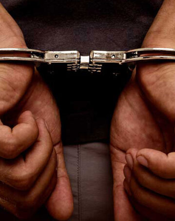 Hands in handcuffs symbolizing arrest or detention.
