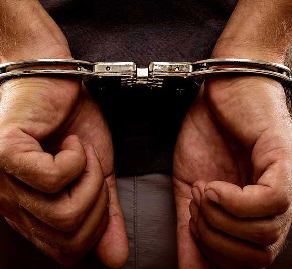 Hands in handcuffs symbolizing arrest or detention.