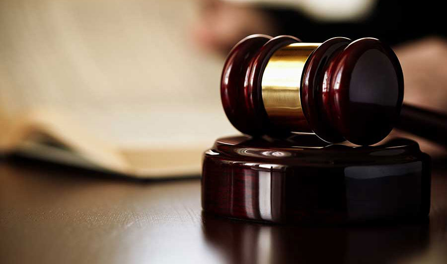 A judge's gavel resting on a wooden sound block.