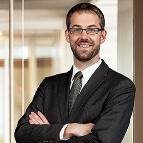 Confident businessman in a suit and glasses with arms crossed.