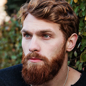 Portrait of a bearded man with blue eyes outdoors.