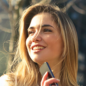 Smiling young woman holding a vape outdoors.
